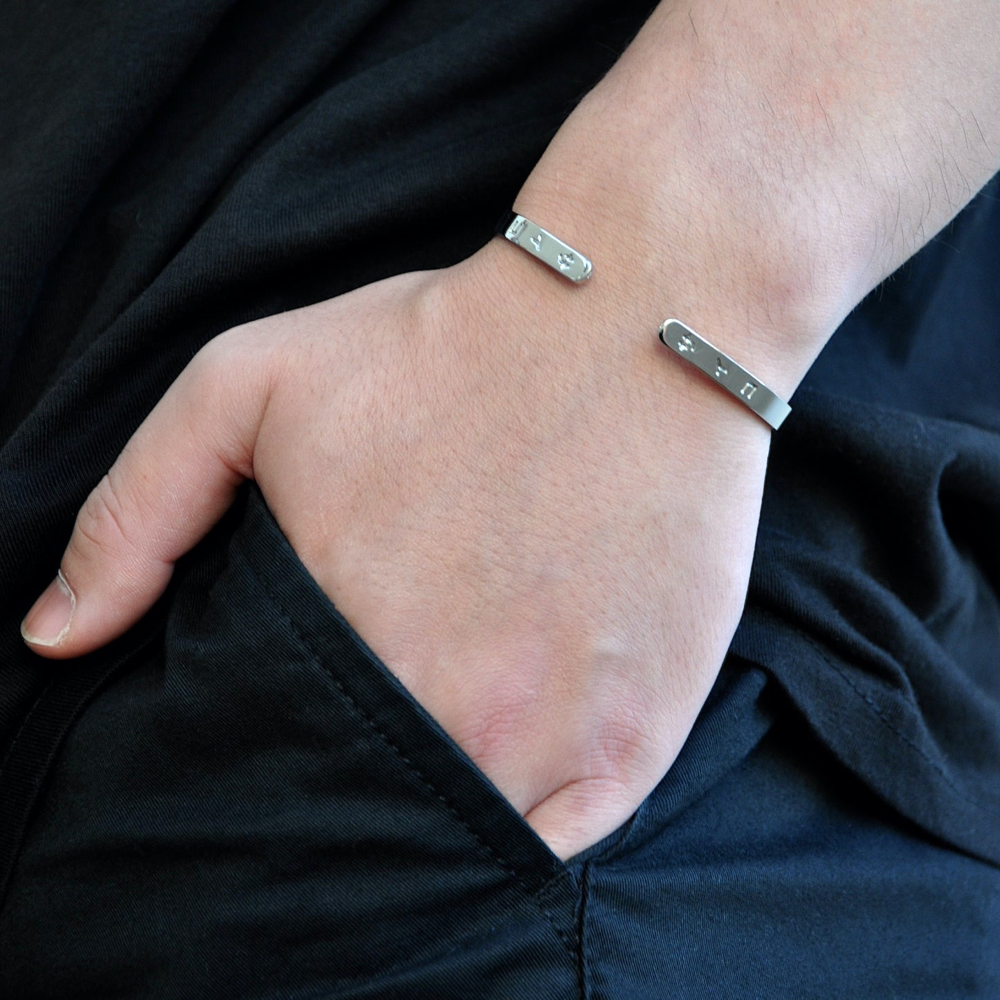 male man boy hand in pocket wearing silver cuff bracelet made from 316L polished stainless steel with japanese character logo engraved onto the signet