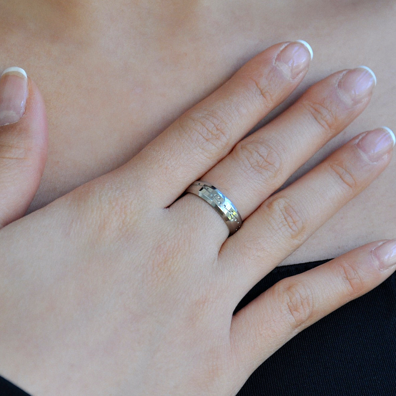 close up of woman girl female finger and hand wearing silver band ring made from 316L polished stainless steel with japanese character logo and cherry blossom sakura design engraved onto the ring