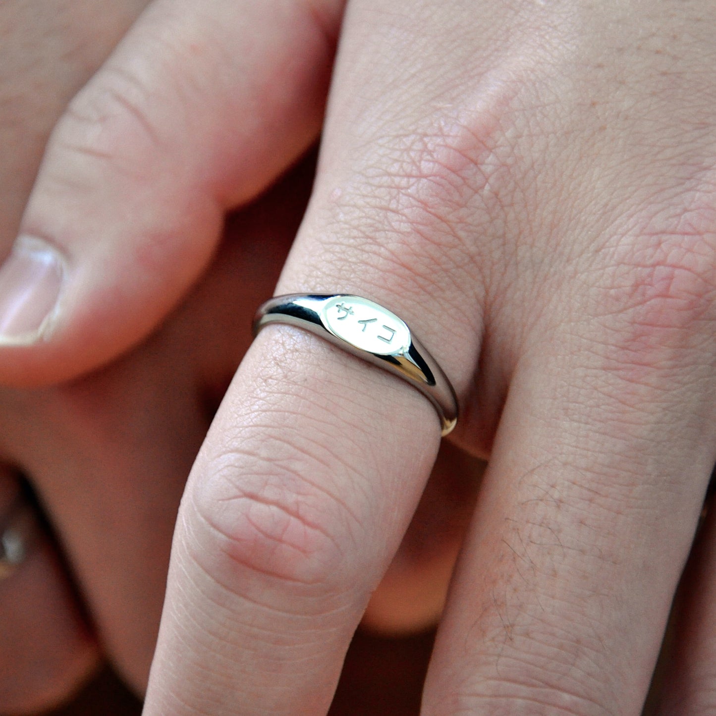 close up of male man boy fingers wearing silver signet ring made from 316L polished stainless steel with japanese character logo engraved onto the signet