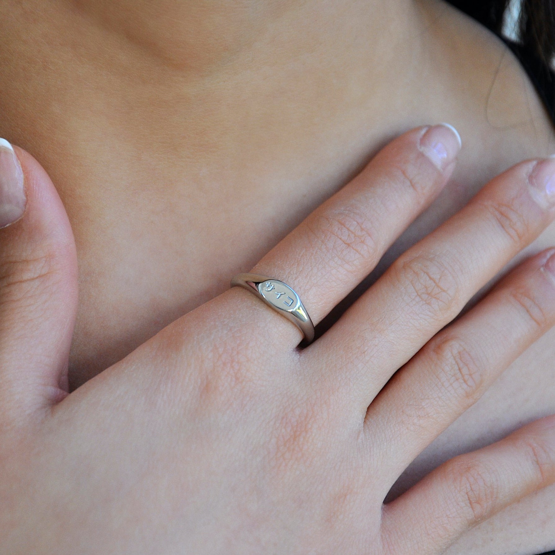 female woman girl wearing silver signet ring made from 316L polished stainless steel with japanese character logo engraved onto the signet