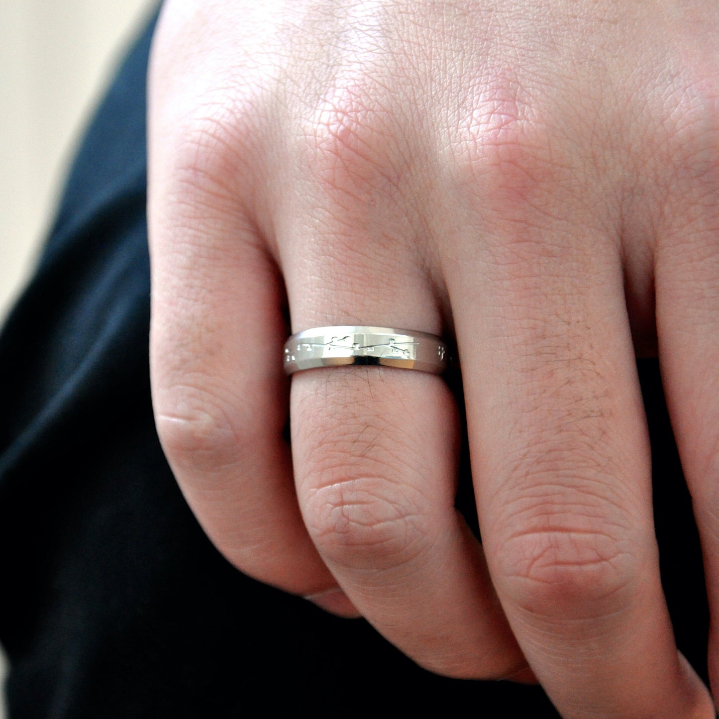 close up of male boy man hand and finger silver band ring made from 316L polished stainless steel with japanese character logo and cherry blossom sakura design engraved onto the ring