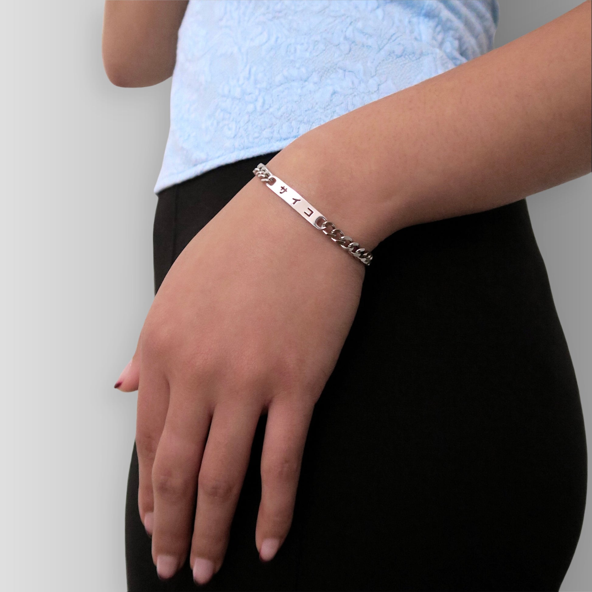 Girl with a blue top wearing 316L stainless steel cuban chain bracelet with Japanese SAIKO logo