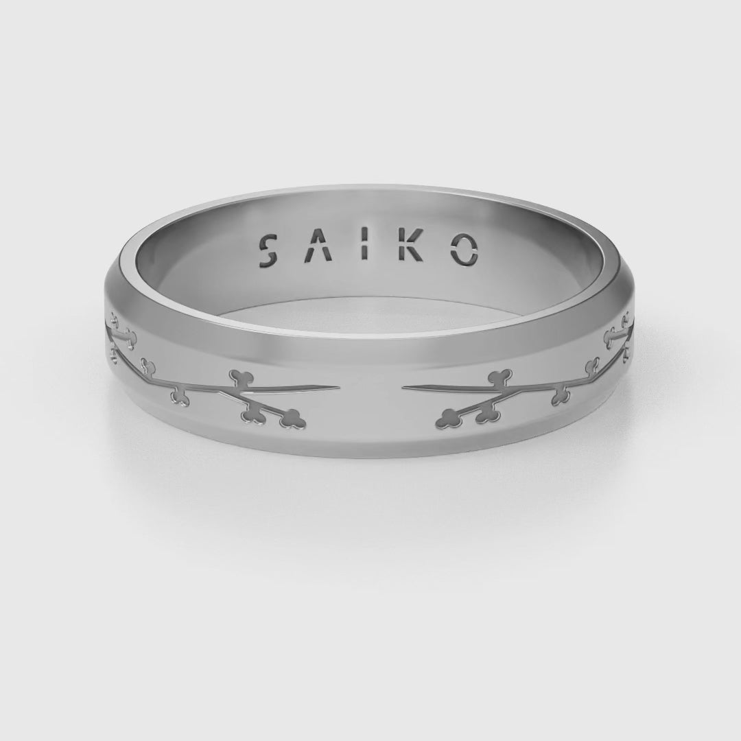 Silver stainless steel 316L ring with cherry blossom engraving placed on the ground rotating 360 degrees with a white background